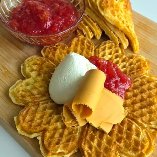 Norwegian heart waffles with cardamom, dusted with powdered sugar on a wooden board