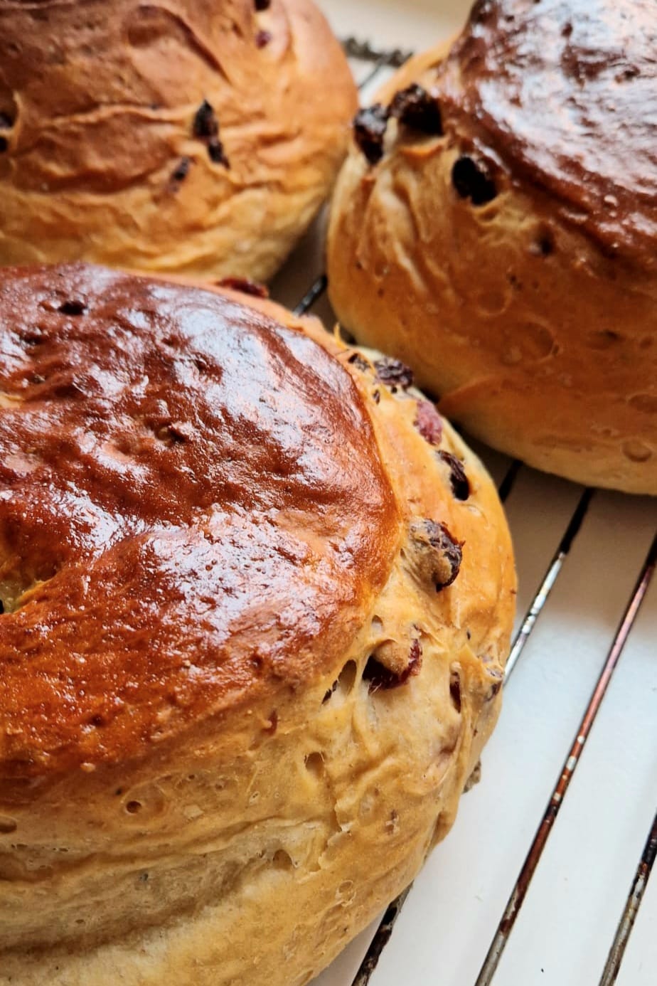 Norwegian julekake, a golden glazed Christmas bread studded with raisins, on a wooden board
