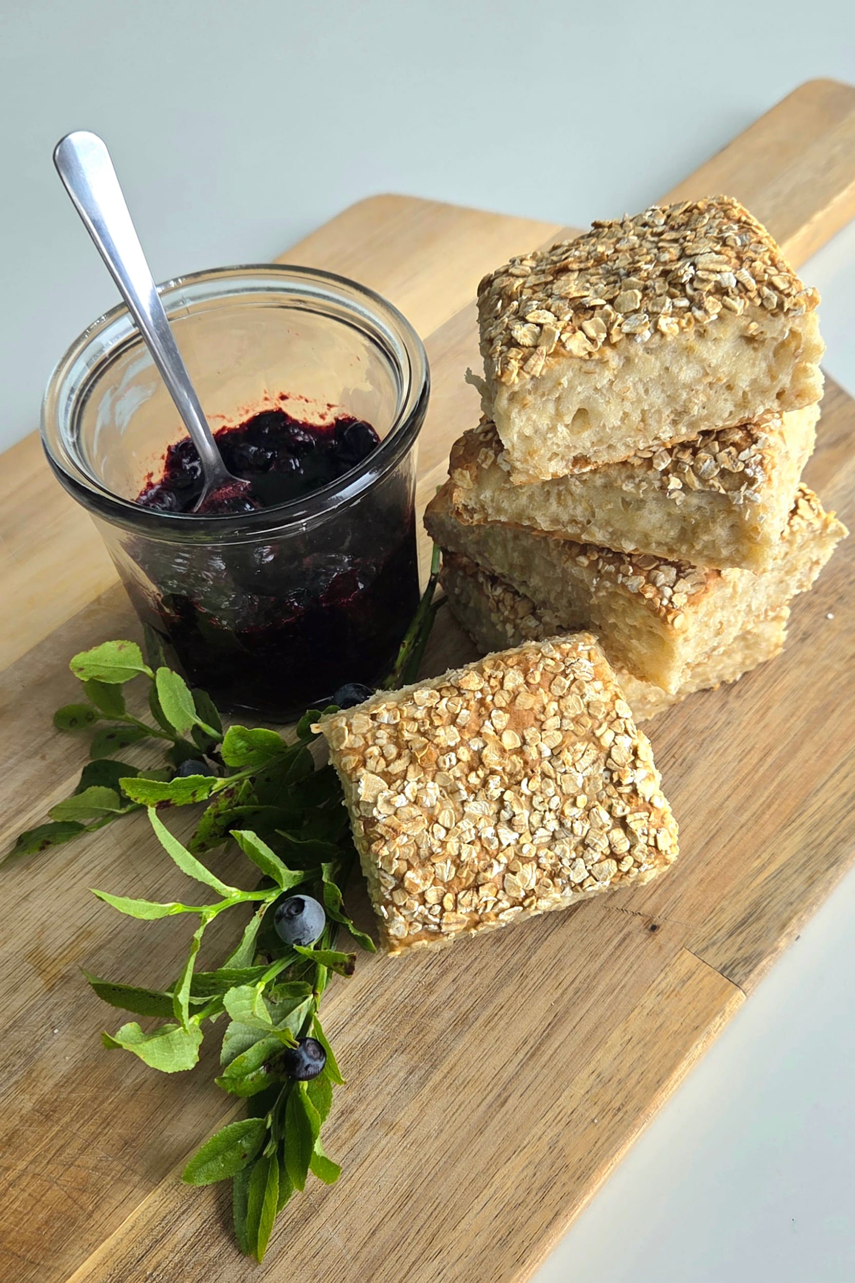 Golden oat scones on a wooden board, baked as one tray and broken into squares, topped with rolled oats