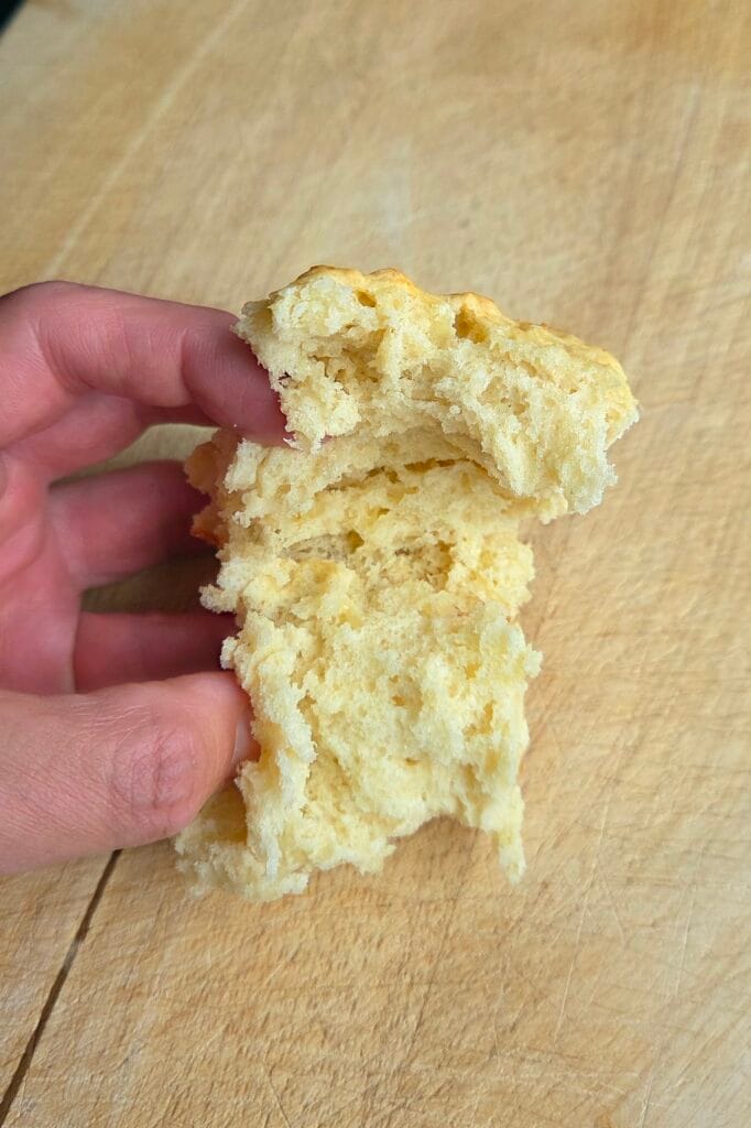 Hand pulling a cheese scone apart to show the soft, bready pull-apart crumb