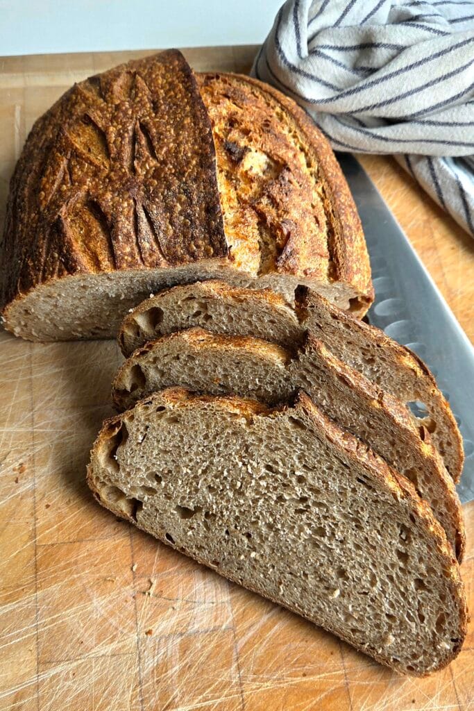 Two-day-old sourdough loaf sliced on a wooden board, still with a crisp crust and moist crumb