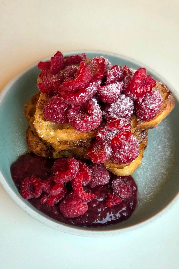 Stack of Norwegian French toast with raspberry jam and fresh raspberries