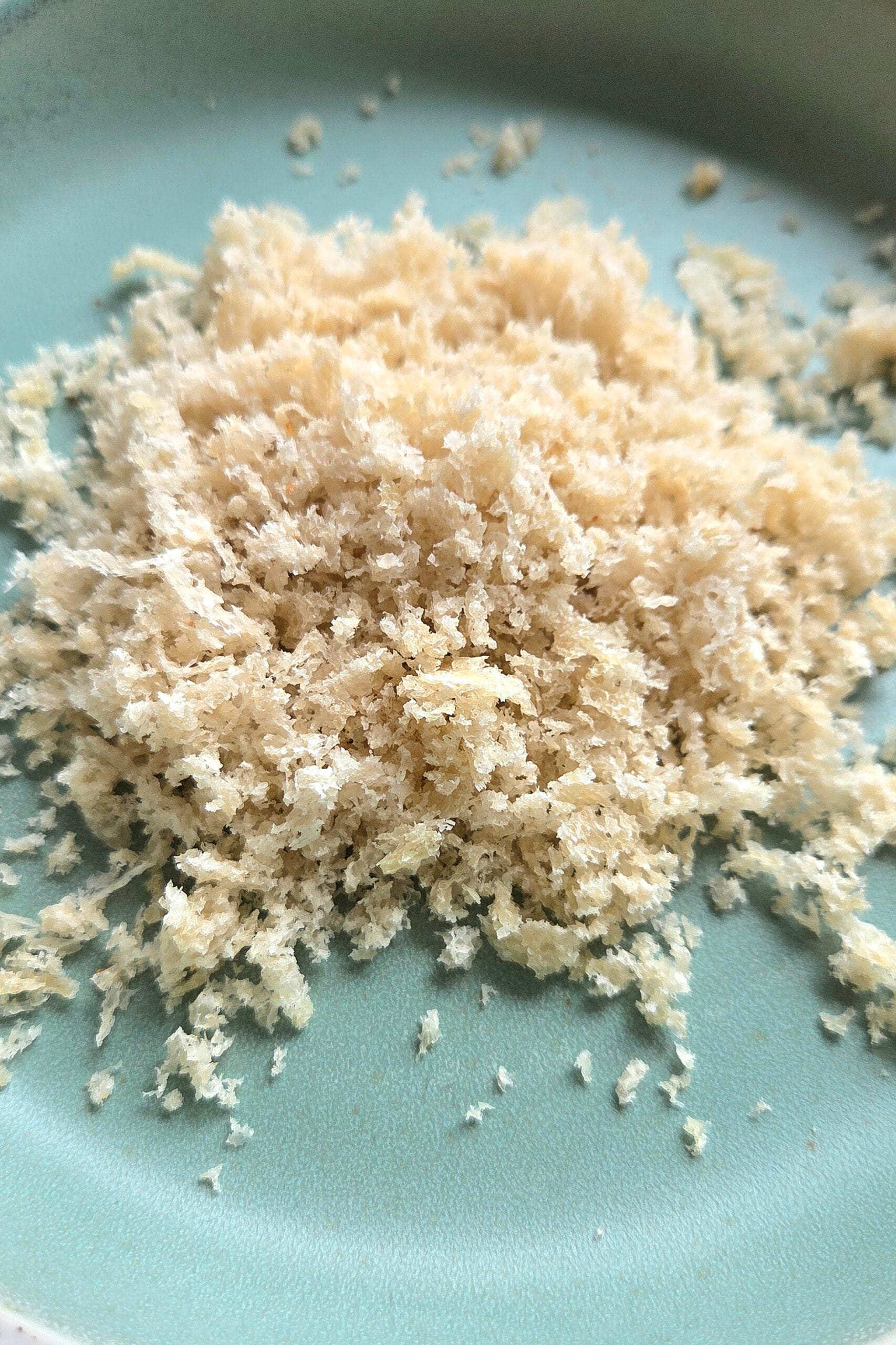 Pale, flaky homemade sourdough panko on a green plate after drying in a low oven