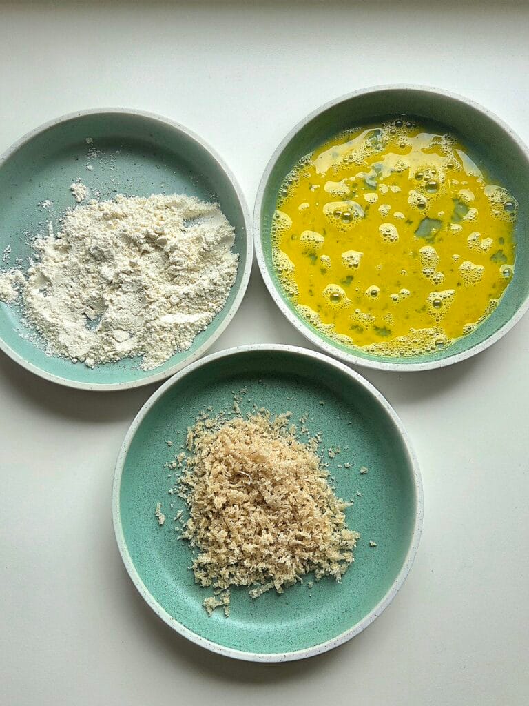 Flour, beaten egg and sourdough panko set up in three bowls for breading root vegetables