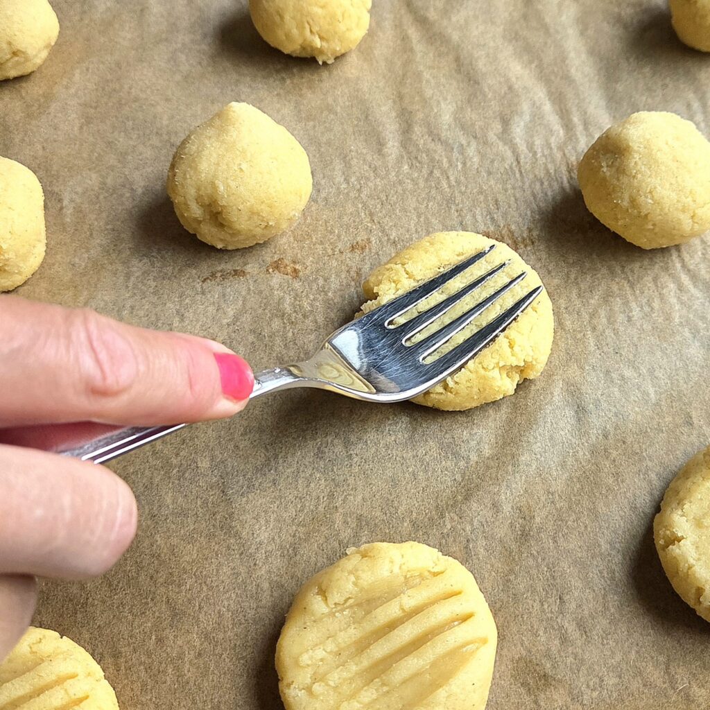 Pressing serinakaker dough with a fork to make the ridged pattern