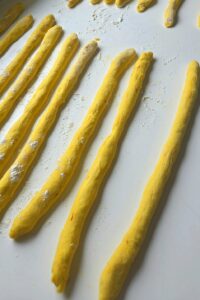 Saffron dough rolled into long, even ropes for shaping lussekatter