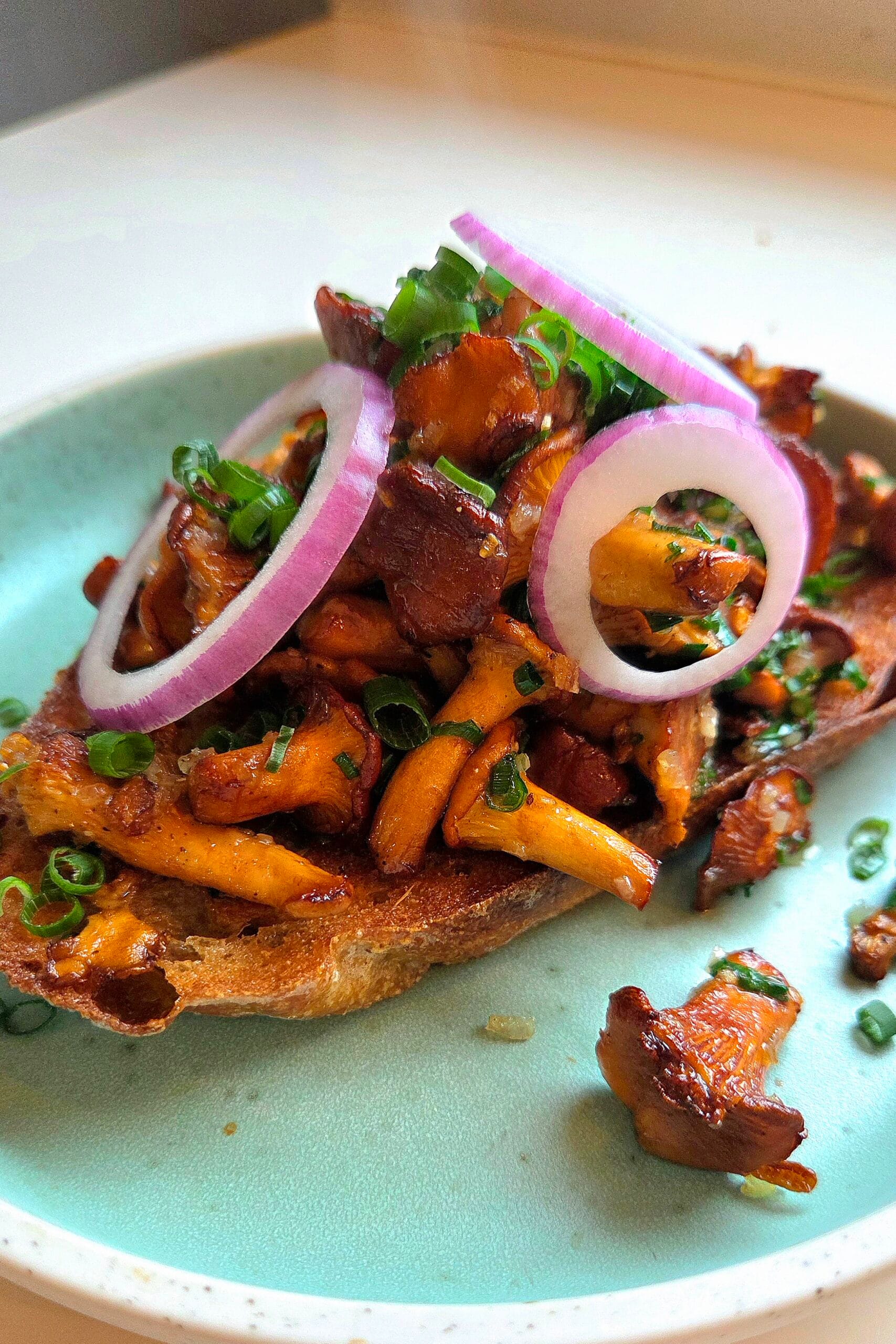Chanterelle toast on fried sourdough topped with chives and red onion rings