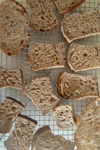 Slices of whole grain sourdough bread drying on a wire rack to make sourdough breadcrumbs