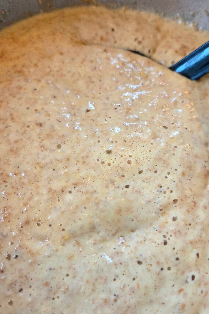 Rested yeasted savory waffle batter with bubbles on the surface in a bowl