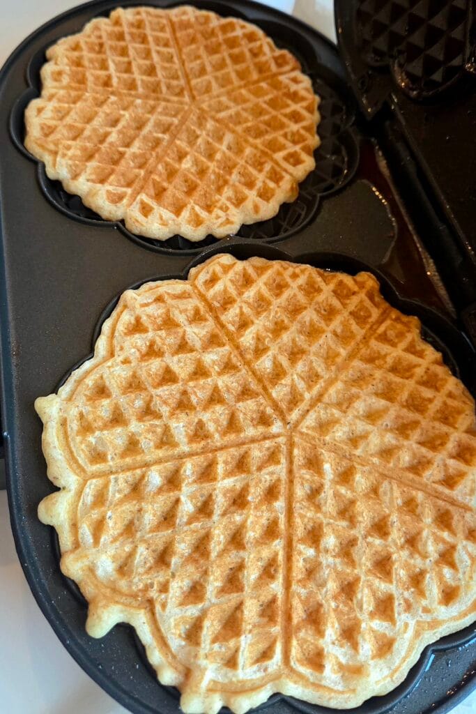 Golden savory waffles cooking in a Norwegian heart-shaped waffle iron
