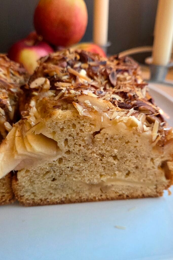 Close-up of the soft crumb of a Norwegian apple cake with visible apple slices and a crunchy almond topping