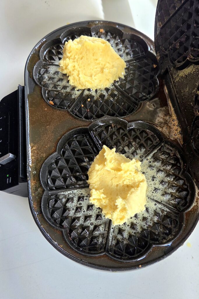 Batter for crispy Norwegian waffles in a buttered heart-shaped waffle iron