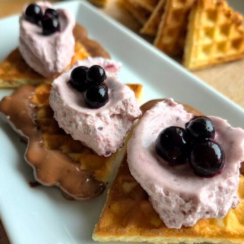 Crispy Norwegian waffles with chocolate and blackcurrant cream on a white plate