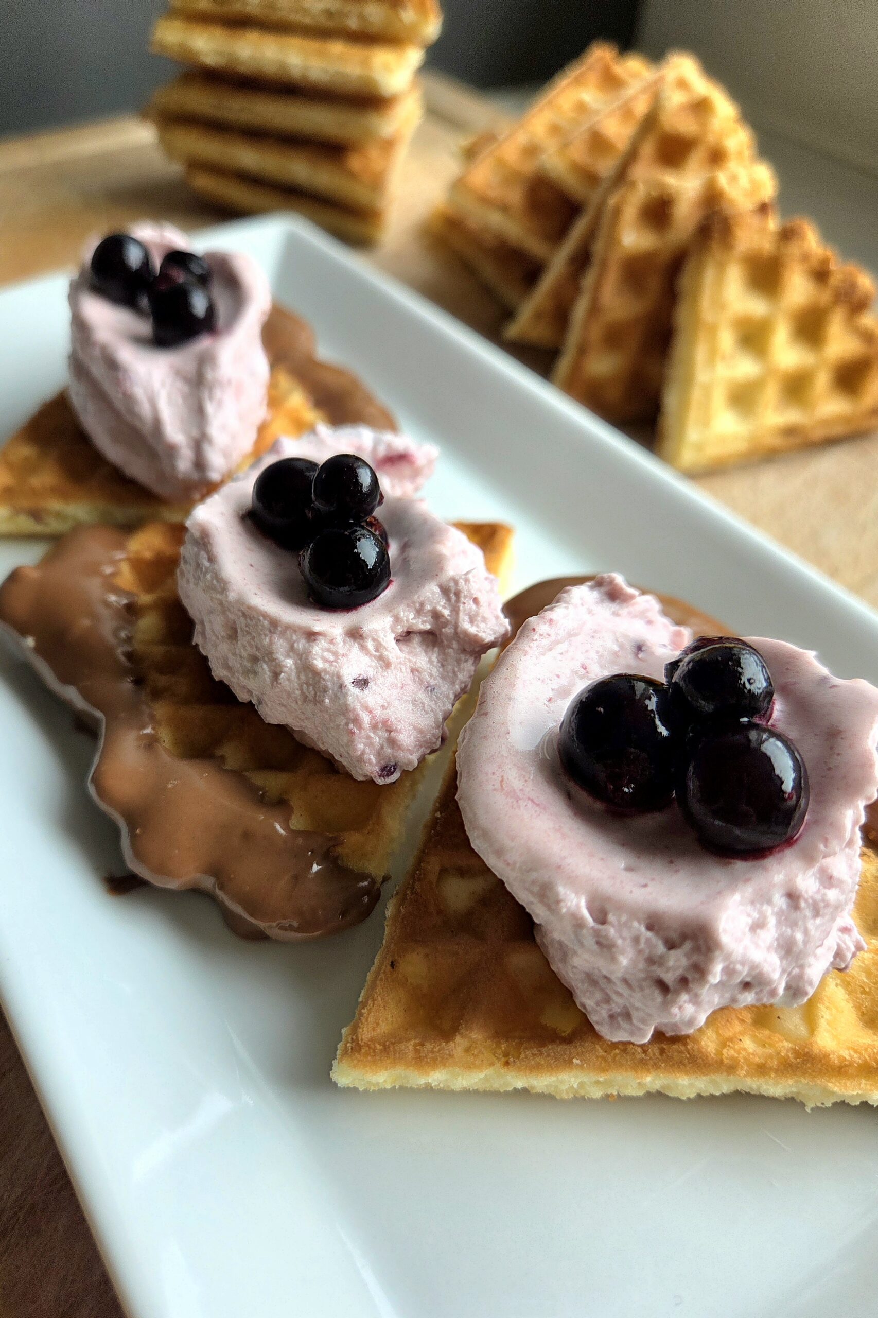 Crispy Norwegian waffles with chocolate and blackcurrant cream on a white plate