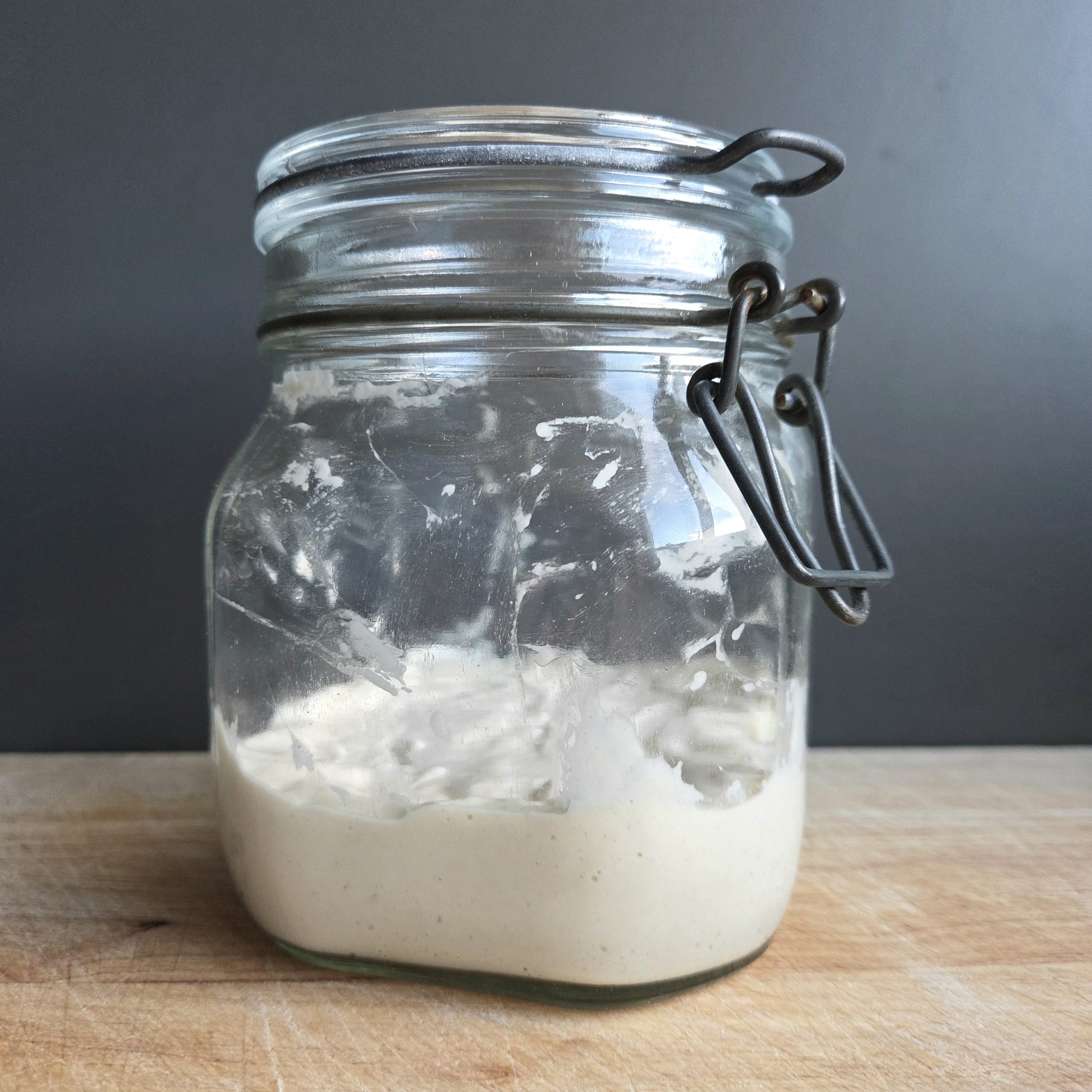 Homemade sourdough starter in a glass jar on a wooden board