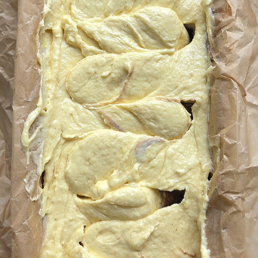 Marble cake batter swirled with a skewer in a loaf pan before baking