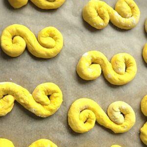 Shaped lussekatter dough in the classic S-curl on parchment paper